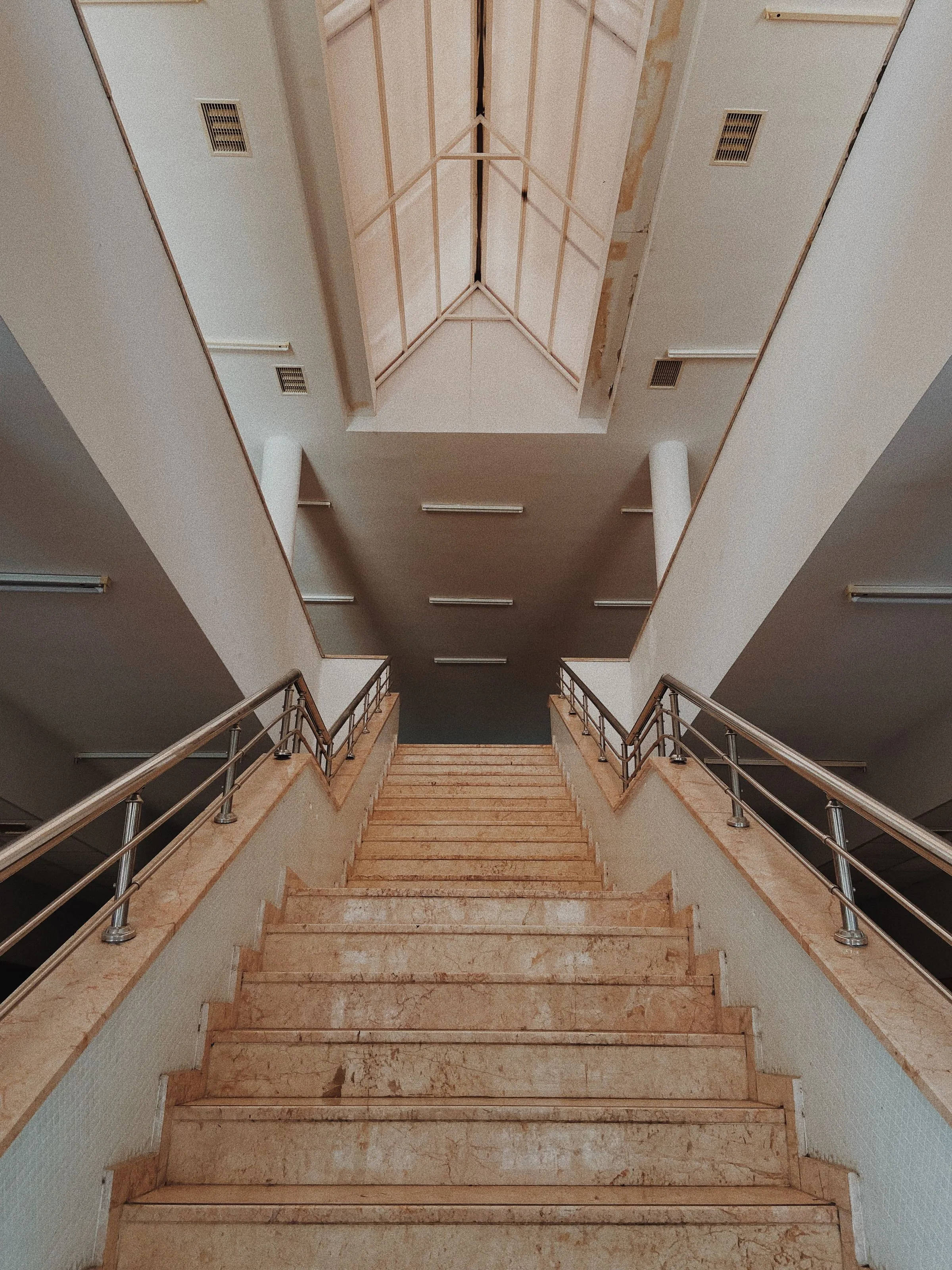 Escalier d'immeuble en marbre beige avec rampes inox