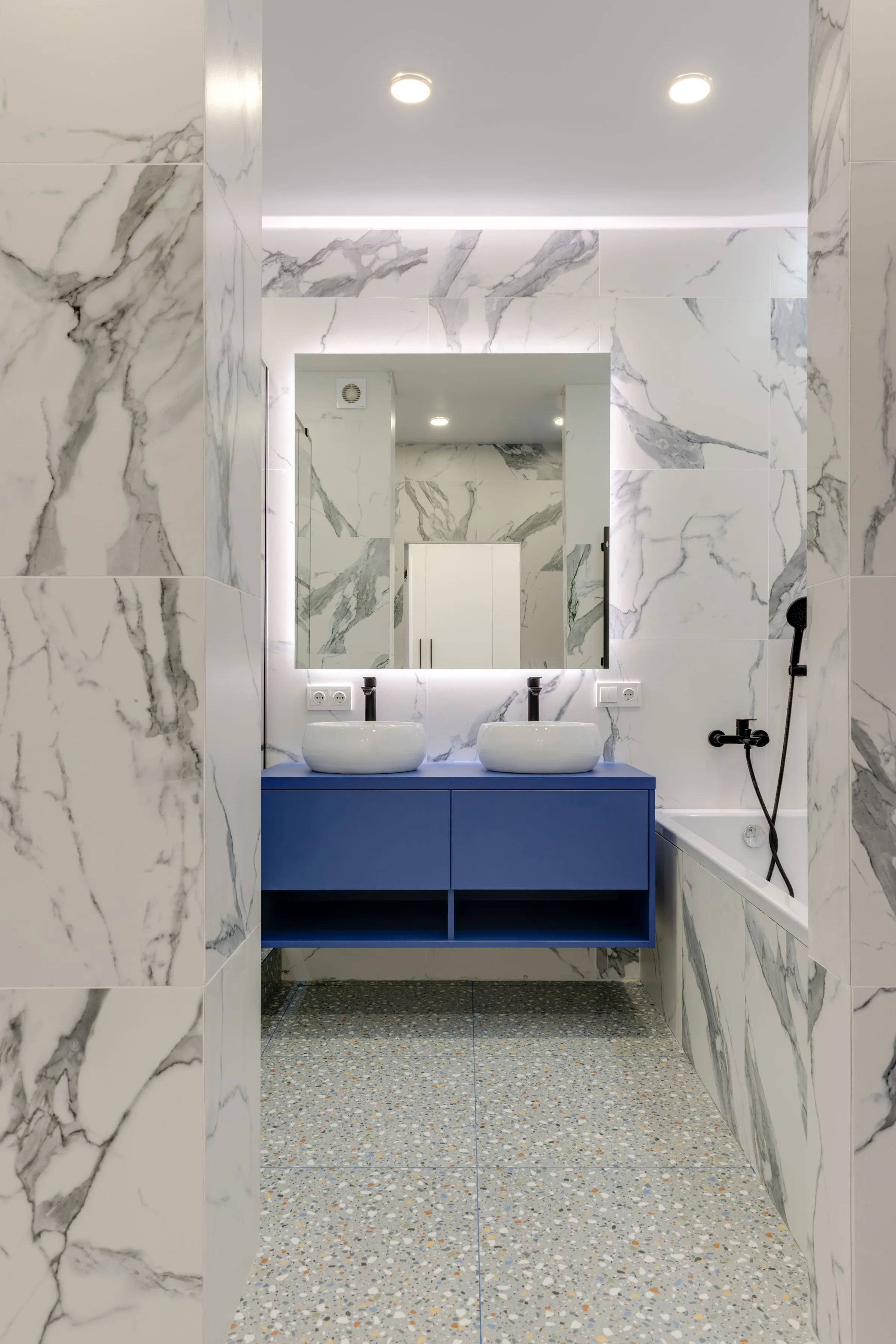 Double vasque blanche sur meuble bleu dans une salle de bain en marbre